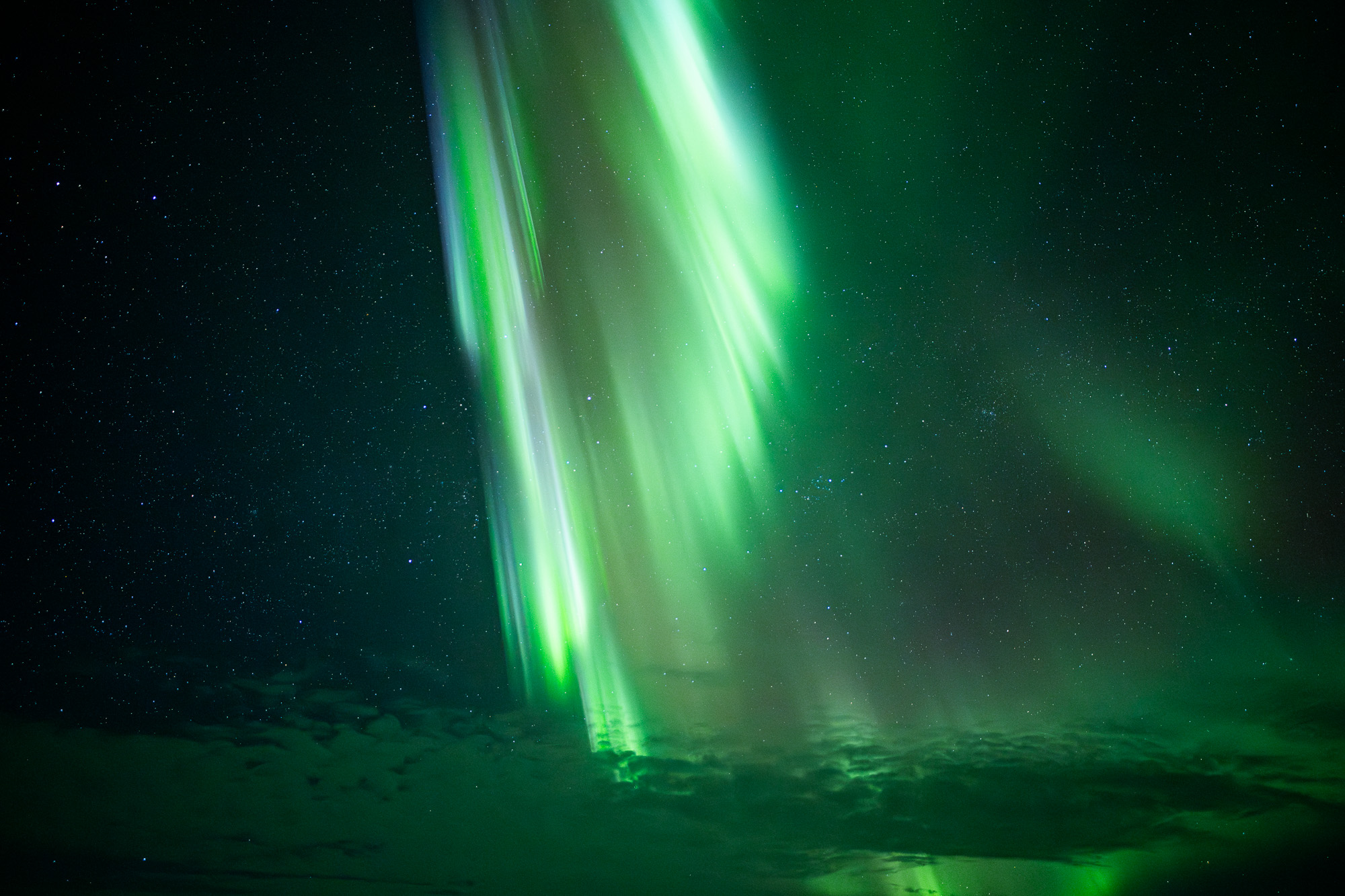 Aurora curtains with clouds in Alaska