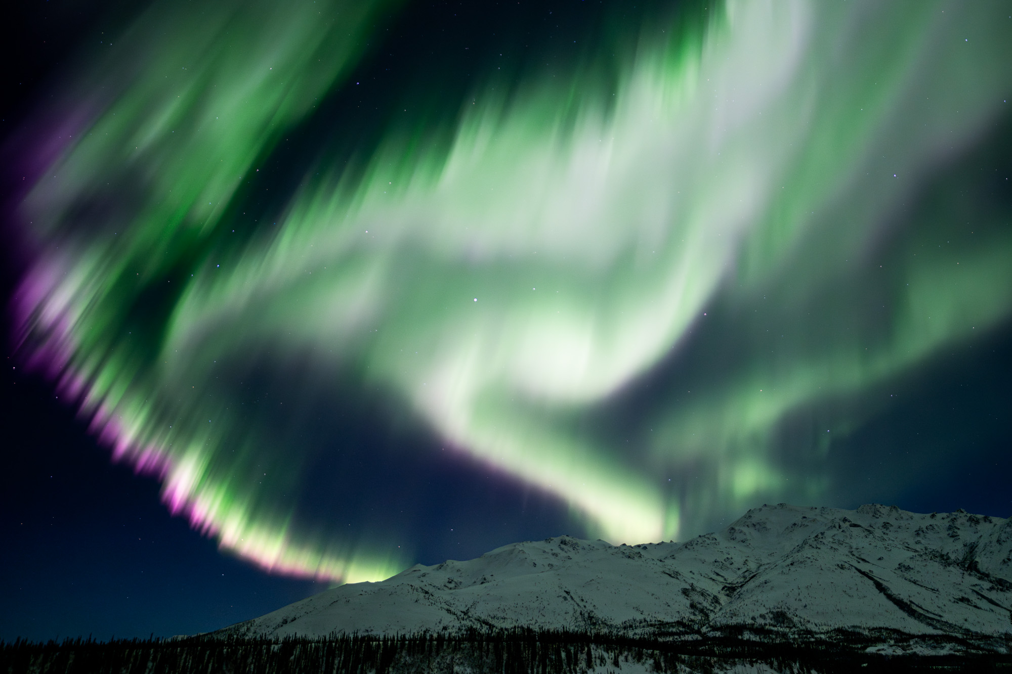 Purple aurora over Alaskan mountains