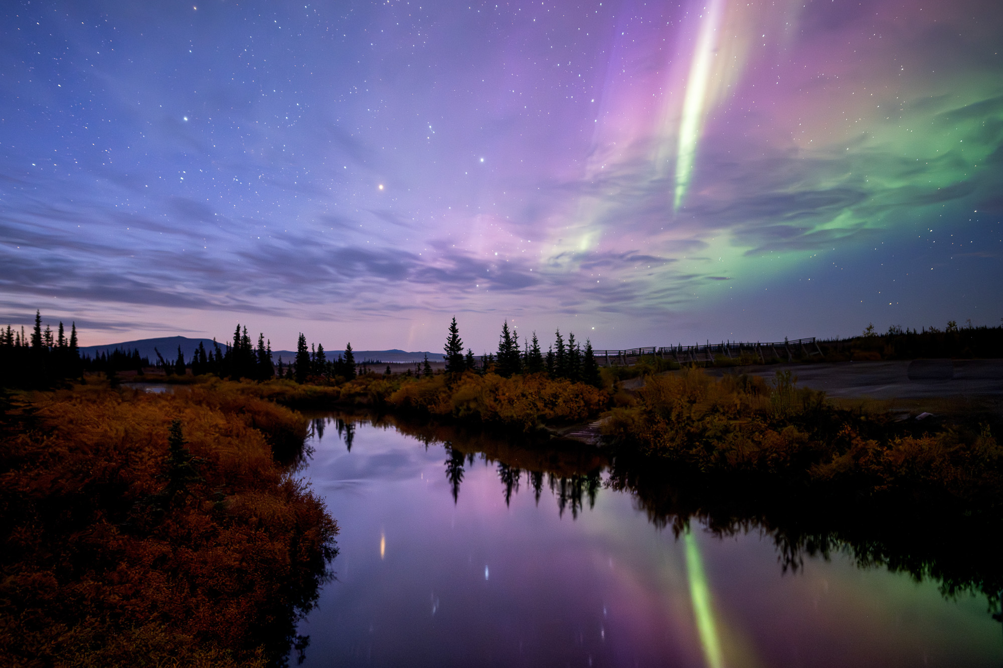 Aurora reflecting on a lake during twilight in Alaska